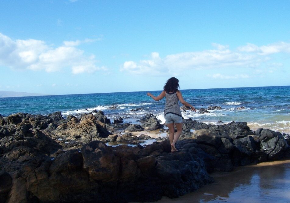 Woman walking on the rocks on the Beach in Hawaii.
